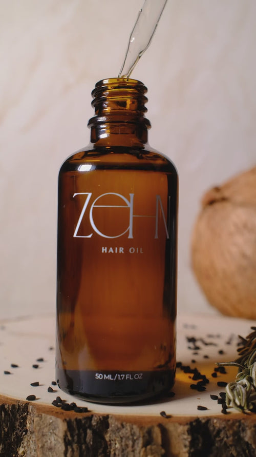 Zehn Hair Oil dropper releasing botanical oil into an amber bottle. Lightweight pre-wash hair and scalp oil handcrafted in Canada.